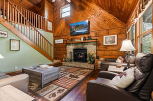 Unwind in your cozy living room with warm wood accents, crackling fireplace, and comfortable leather seating perfect for mountain evenings.