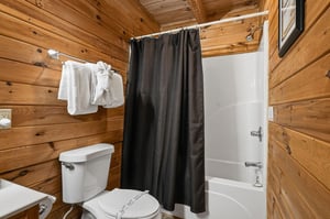 Step into your cozy cabin bathroom, where warm wood paneling meets modern convenience. Fresh towels await, and the tubshower combo invites you to unwind after a day of adventure.