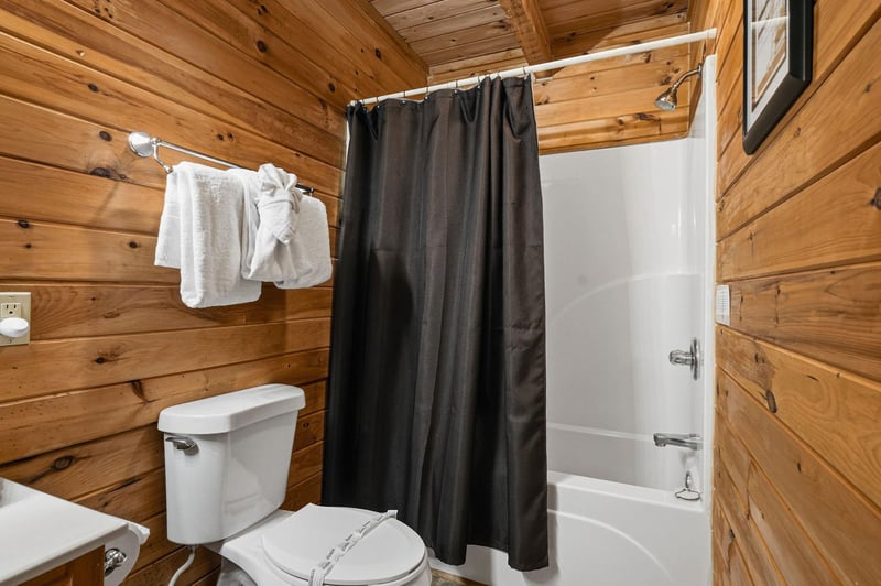 Step into your cozy cabin bathroom, where warm wood paneling meets modern convenience. Fresh towels await, and the tubshower combo invites you to unwind after a day of adventure.