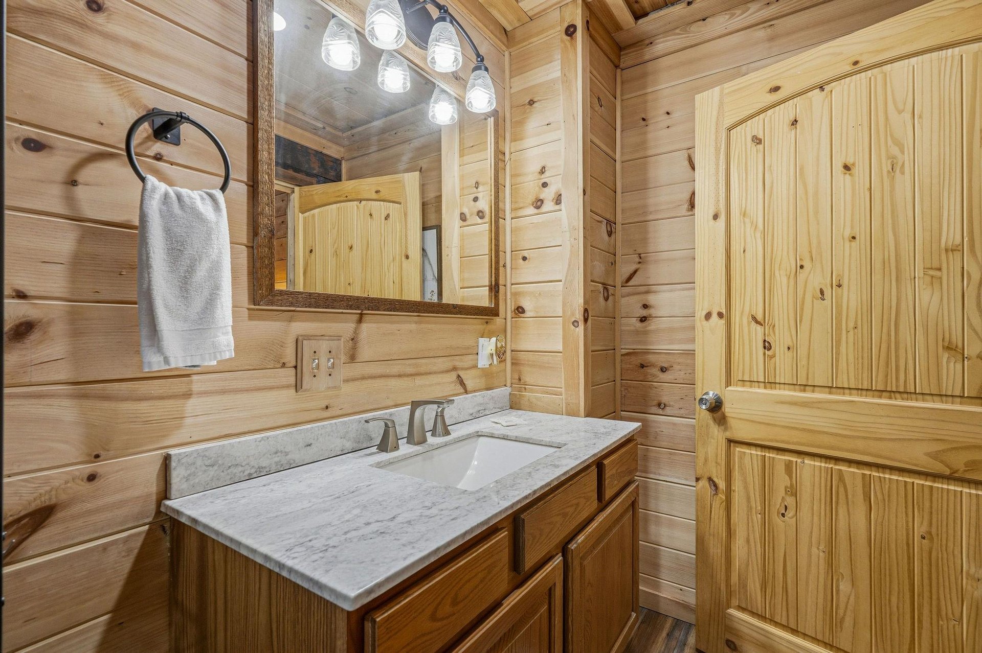 Warm wood paneling surrounds your private bathroom, complete with elegant marble countertops and thoughtful touches like fresh towels ready for your arrival.