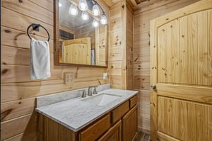 Warm wood paneling surrounds your private bathroom, complete with elegant marble countertops and thoughtful touches like fresh towels ready for your arrival.