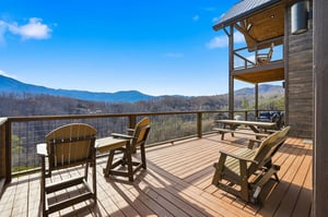 Step onto this expansive deck where cozy Adirondack chairs await your morning coffee ritual amid breathtaking mountain vistas stretching endlessly before you.