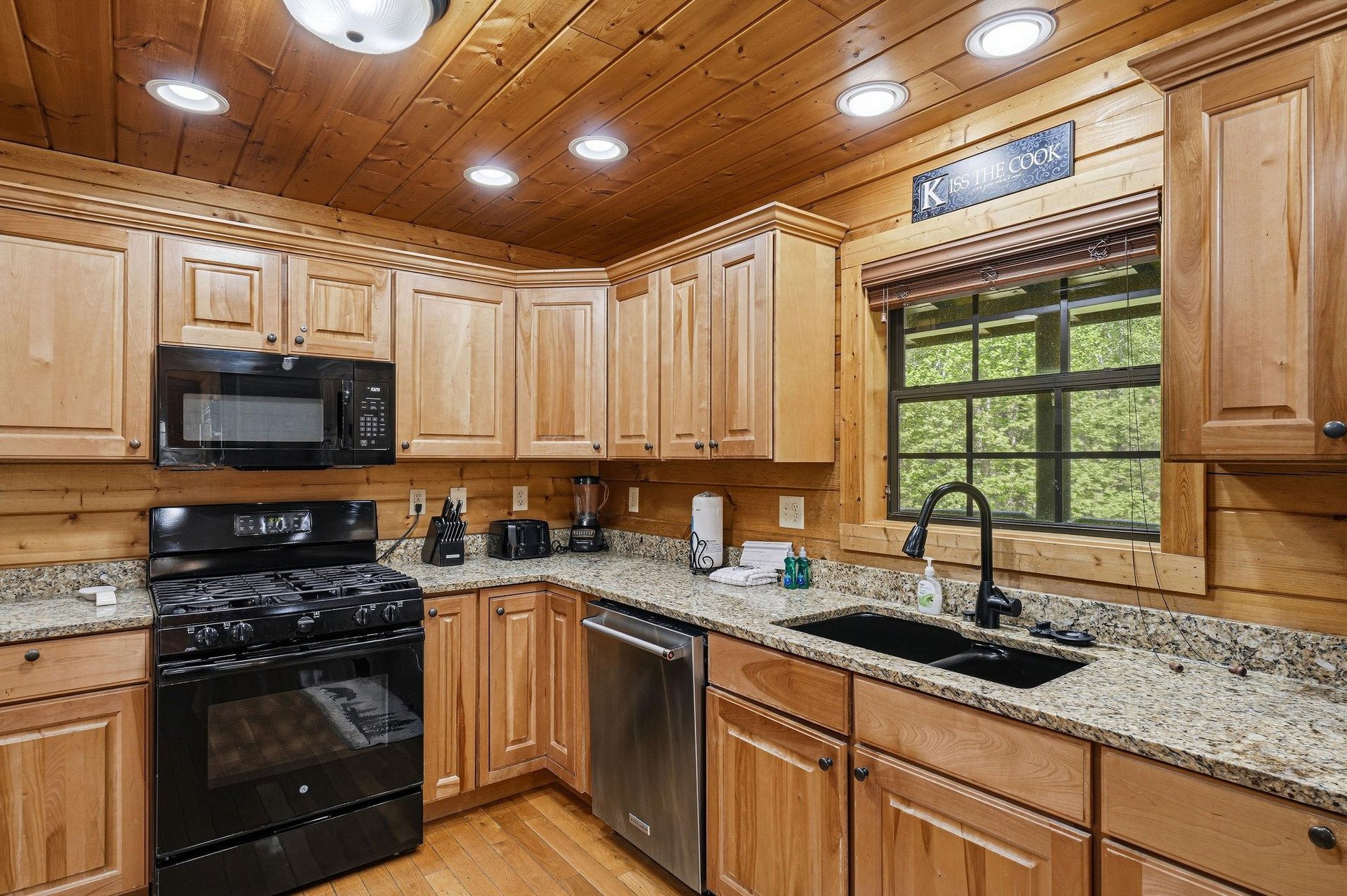Your fully equipped kitchen features granite counters, gas stove, and dishwasher  perfect for preparing meals while enjoying forest views.
