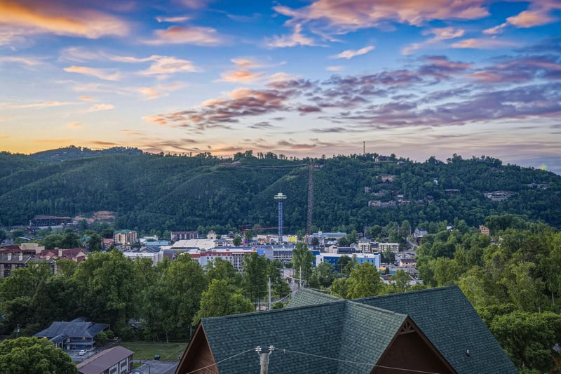 Elevated view showcasing the propertys hillside location amid lush greenery, with vibrant downtown attractions and forested mountains forming a picturesque backdrop.