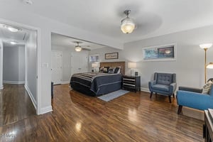 Unwind in your spacious master suite with polished hardwood floors, cozy seating area, and warm ambient lighting creating the perfect retreat.