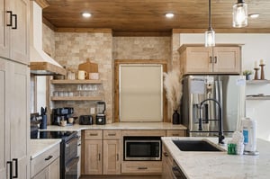 Prepare your favorite meals in this stunning kitchen featuring rustic wood ceilings, modern appliances, and warm pendant lighting for memorable cooking experiences.
