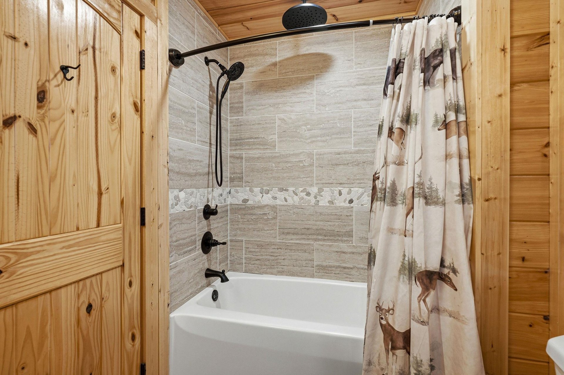 Unwind in your rustic bathroom featuring a modern tubshower combo with rainfall showerhead and charming wildlifethemed curtain.