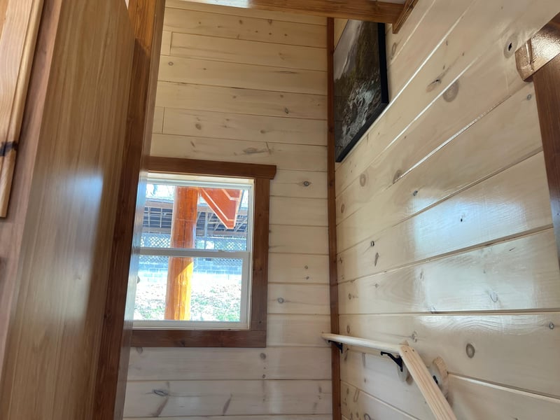 Cozy wooden walls surround you in this intimate space, where natural light streams through your window onto warm timber surfaces.