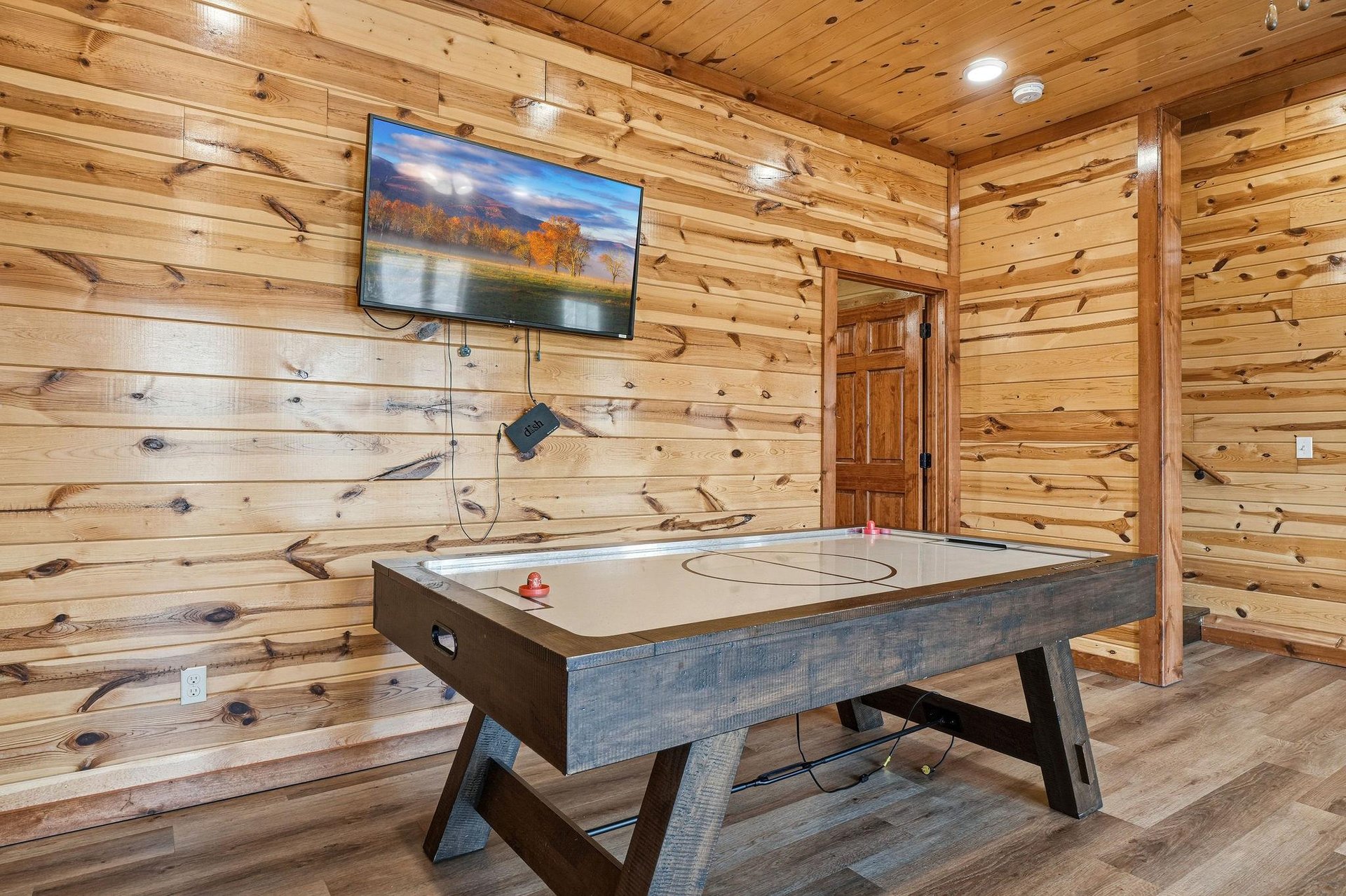 Unwind in your cozy game room featuring air hockey and wallmounted TV, perfect for family fun after mountain adventures.