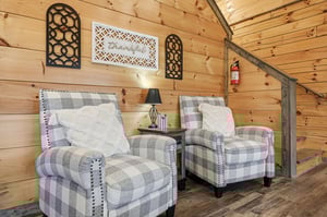 Sink into these plaid armchairs where rustic wood walls create your perfect reading nook with warm cabin charm.