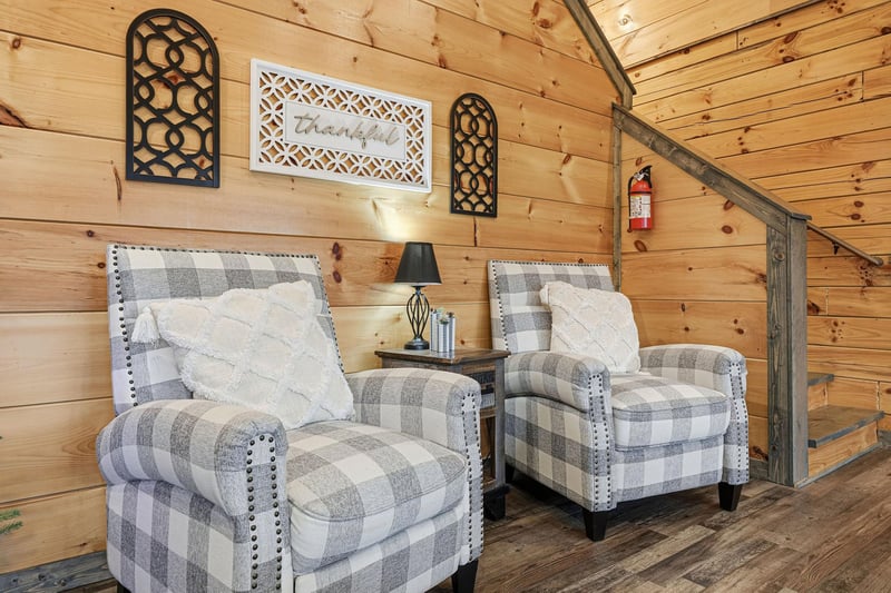 Sink into these plaid armchairs where rustic wood walls create your perfect reading nook with warm cabin charm.
