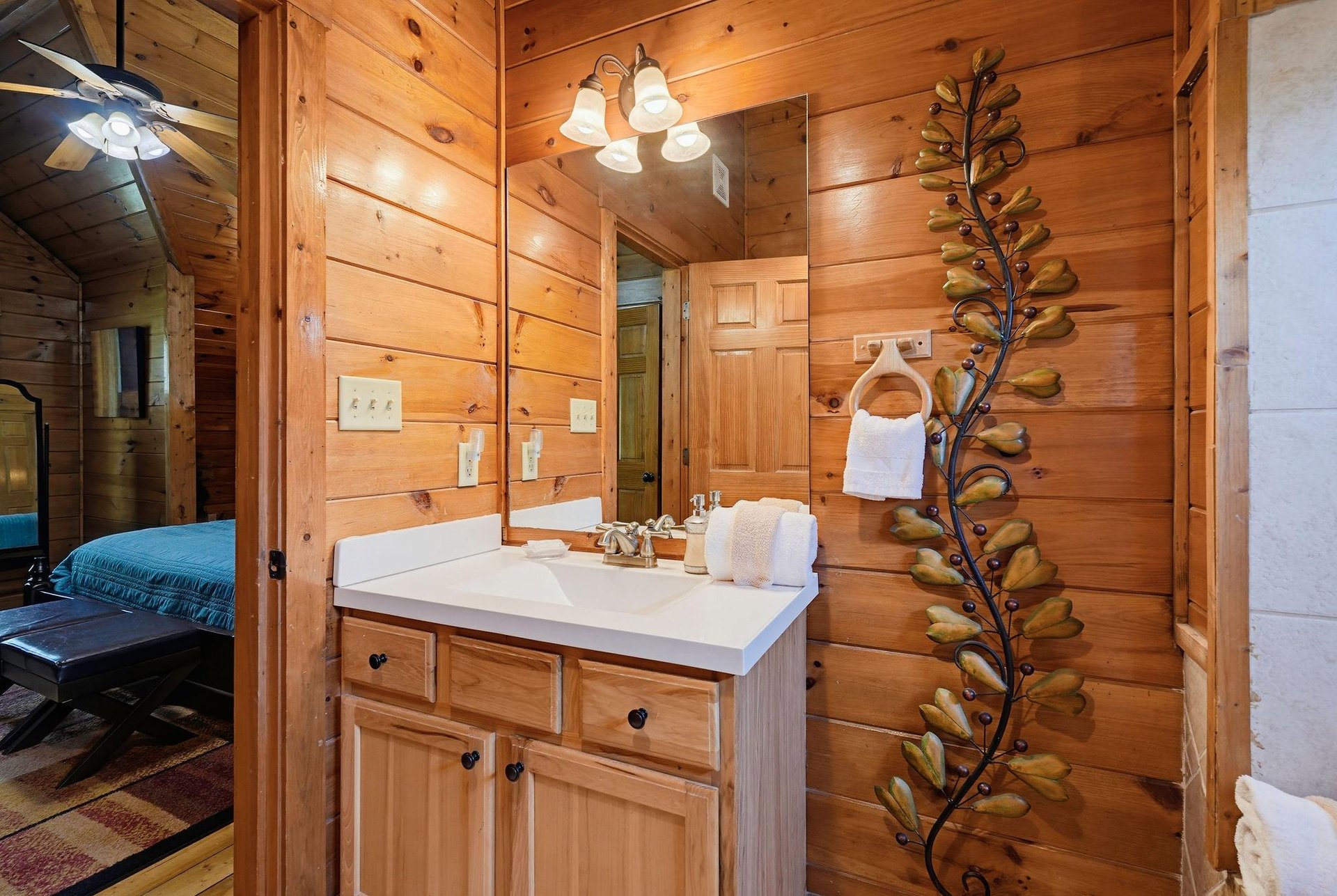 Your private bathroom features warm wood paneling, a spacious vanity, and thoughtful rustic touches like the decorative branch art—a cozy retreat to refresh after your mountain adventures.