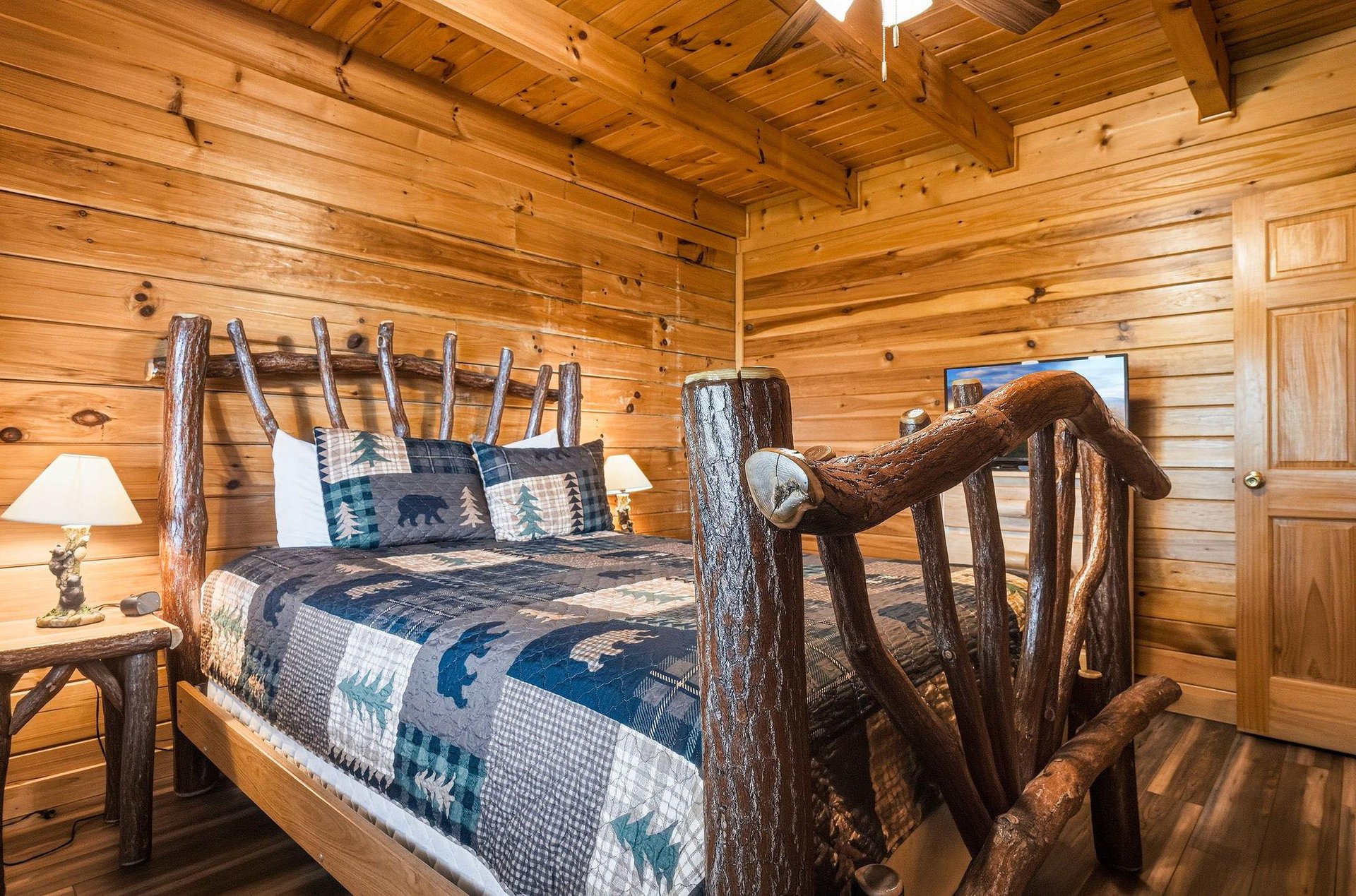 Sink into rustic luxury in this cozy cabin bedroom, where handcarved log furniture and warm wood paneling create your perfect mountain retreat.