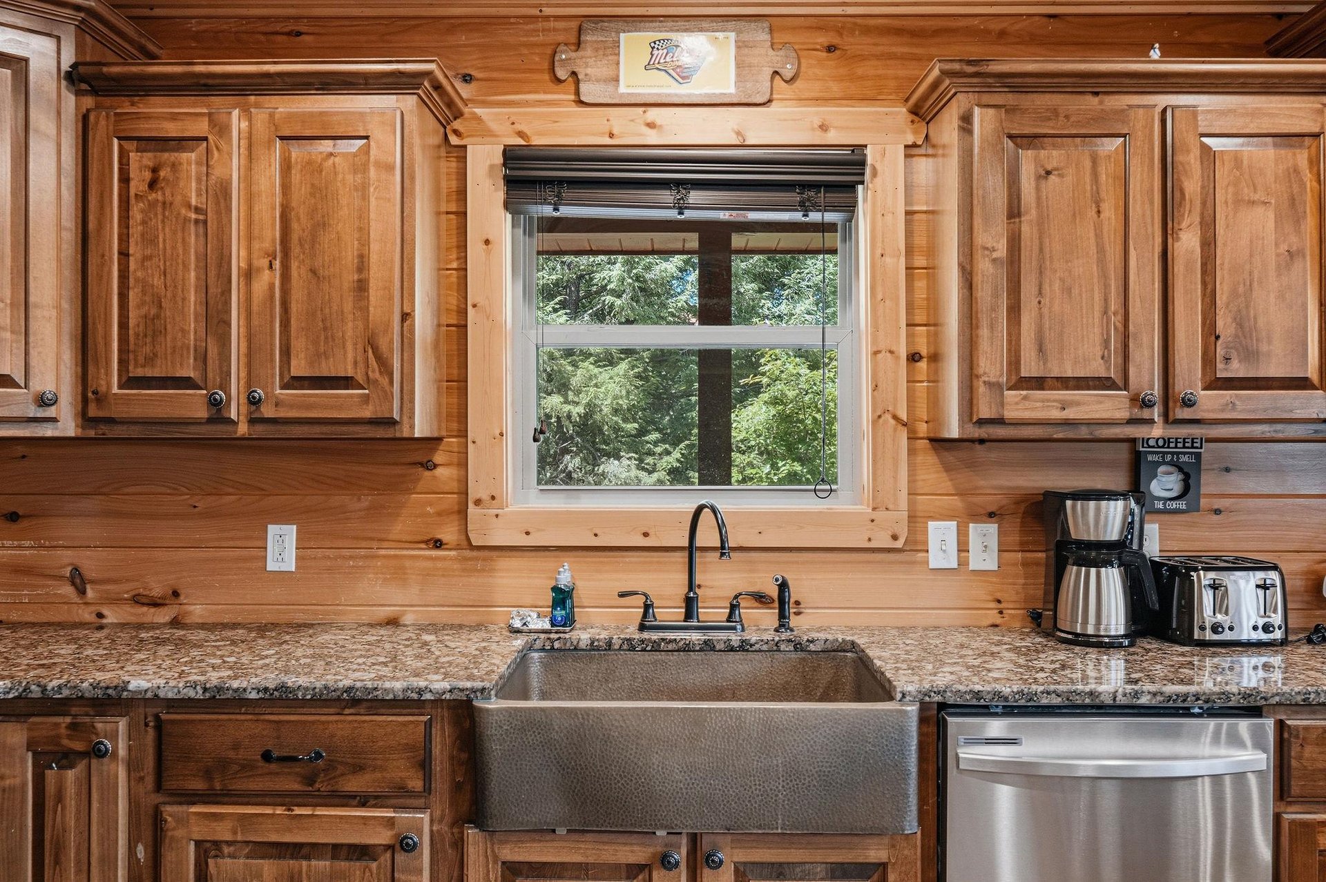 Prepare your favorite meals in a warm, rustic kitchen with modern comforts—farmhouse sink, granite countertops, coffee maker, and a peaceful garden view to inspire your mornings.