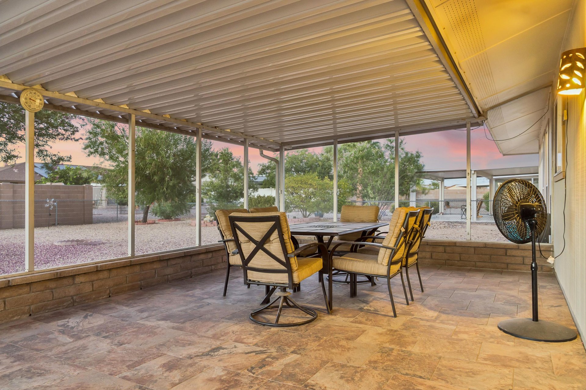 Screened patio with fan, and outdoor dining table and chairs for 6 guests.