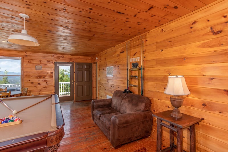 Pool table and loveseat in the game room at Black Bear Ridge, a 3bedroom cabin rental located in Pigeon Forge