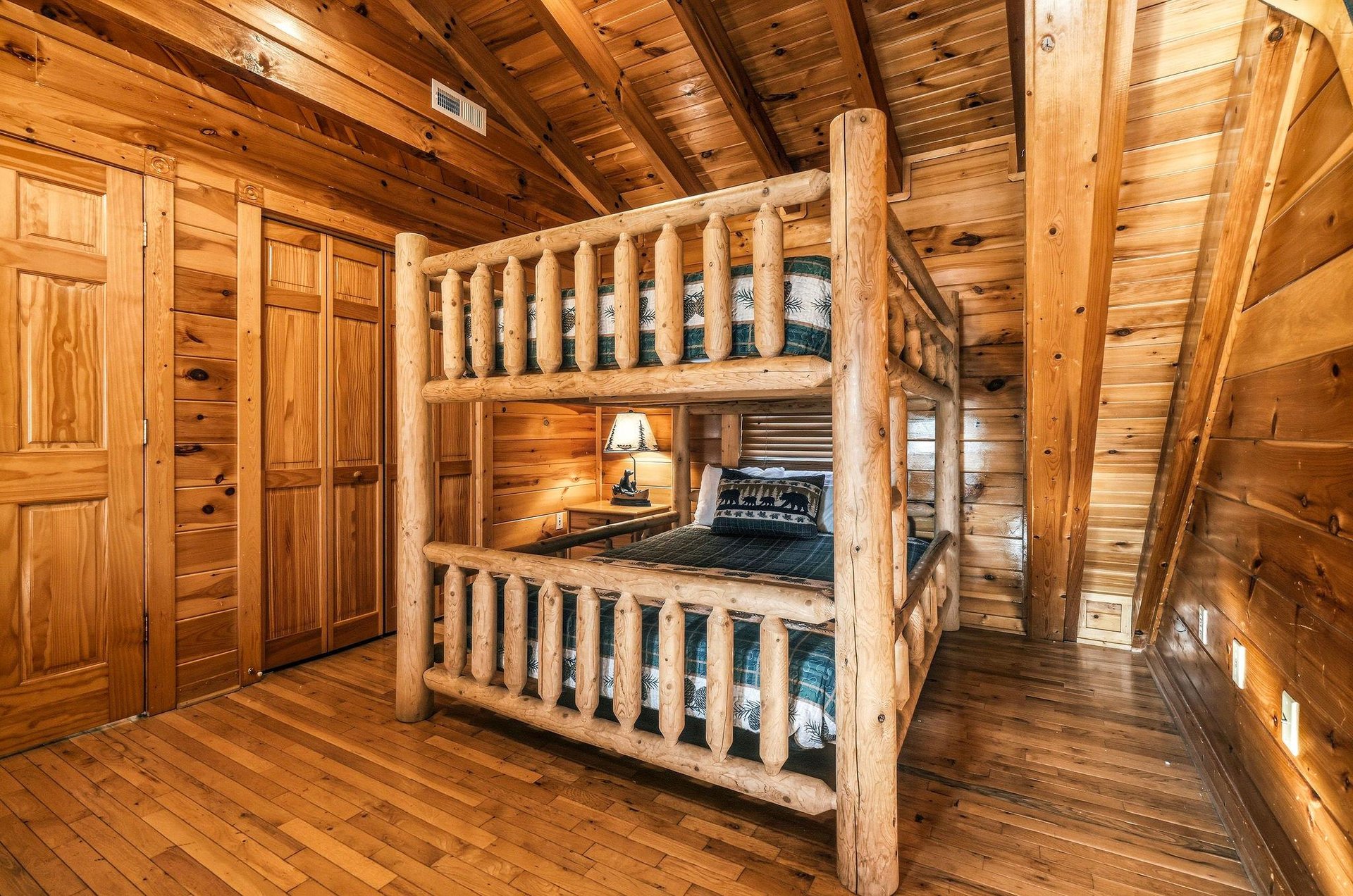 Rustic charm meets cozy comfort in this beautiful loghewn bunk bed with plaid bedding, perfect for family bonding under vaulted wood ceilings.