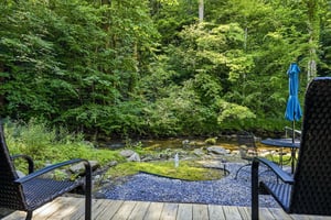 A tranquil stream flows past this peaceful outdoor retreat, where you can unwind in cushioned seating surrounded by lush forest. Listen to the gentle babble of water and breathe in the fresh mountain 