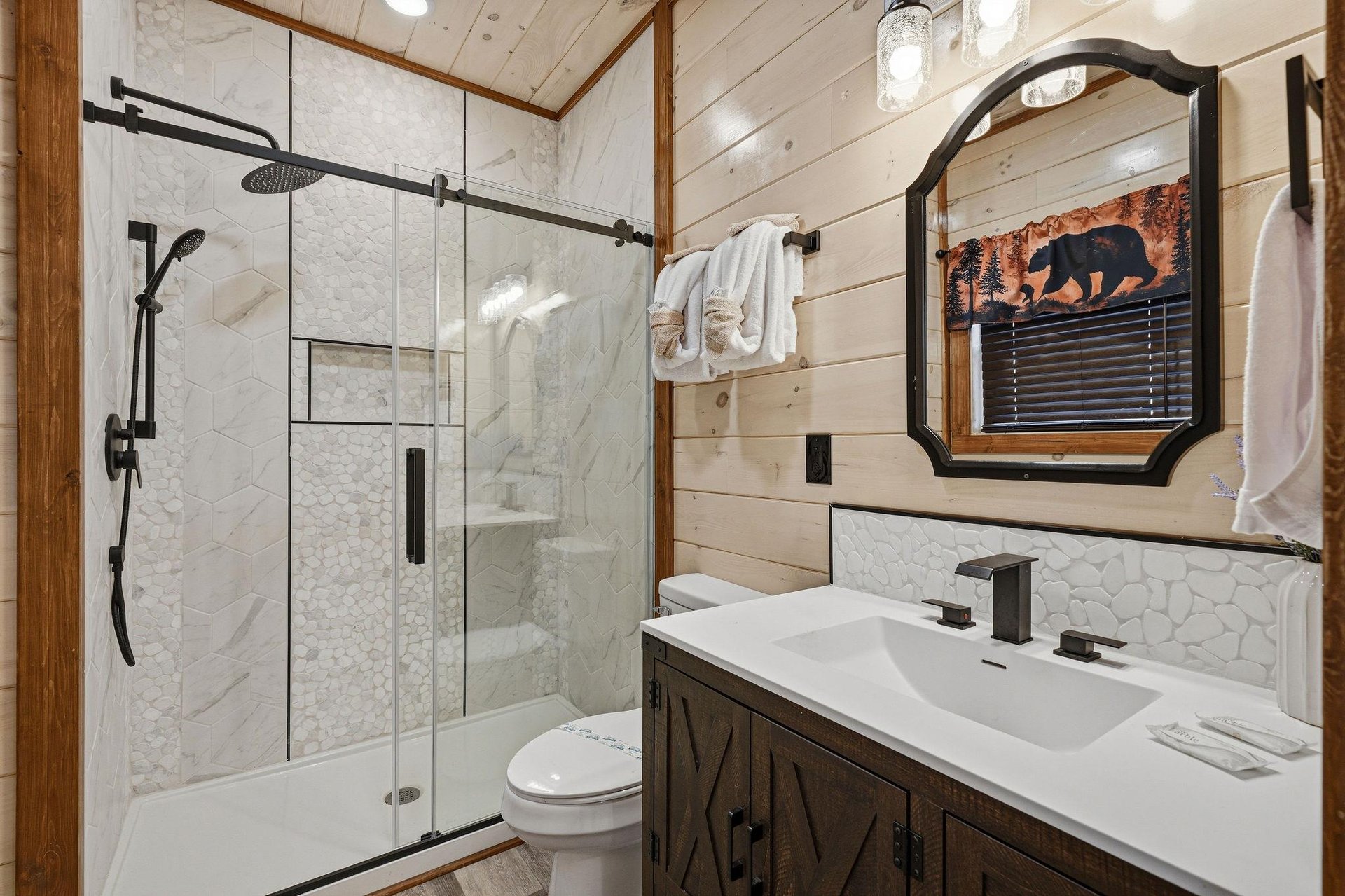 Step into your beautifully appointed bathroom featuring marble walls, rustic wood accents, and a spacious walkin shower with modern fixtures.