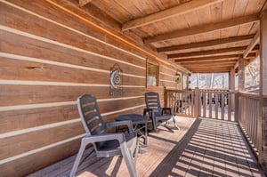 Your private covered deck offers cozy seating where you can unwind with morning coffee or evening conversations surrounded by rustic charm.