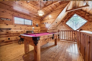 Challenge friends to pool in your cozy loft game room, where warm wood and mountain views create the perfect retreat atmosphere.