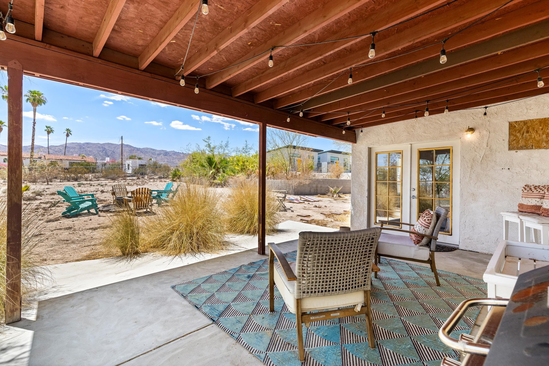 Back patio with string lights, BBQ, outdoor seating, fire pit, hot tub, and corn hole.