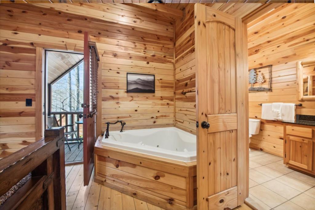 Unwind in your private log cabin bathroom featuring a luxurious soaking tub surrounded by warm pine walls and peaceful mountain views.
