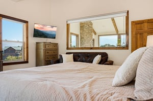 Sink into a plush bed with textured linens and wake to stunning mountain views through large windows. A cozy sitting area and rustic touches make this your peaceful retreat.