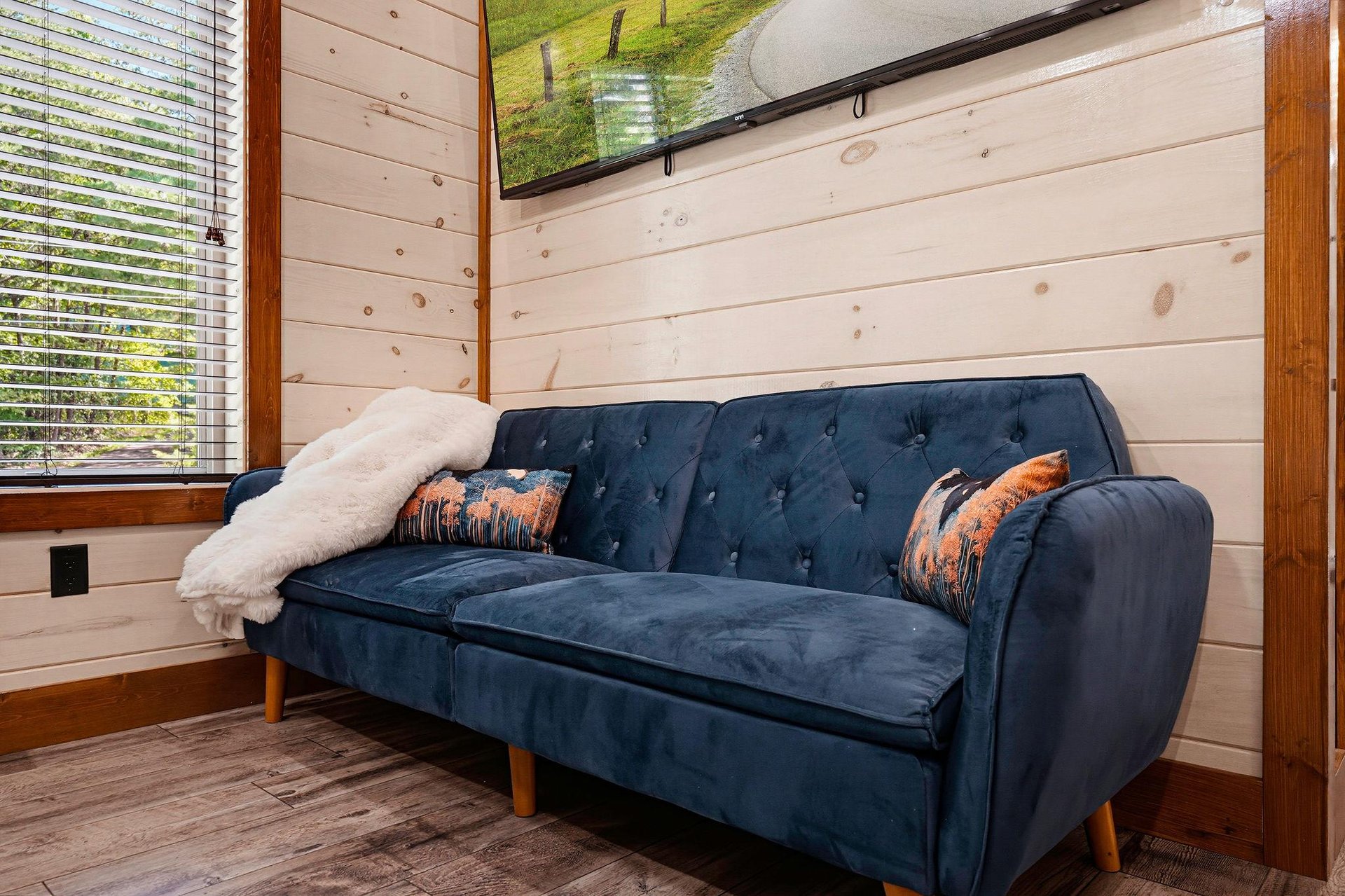 Sink into this plush velvet sofa and unwind beneath the skylight. Natural light pours in, warming the woodpaneled walls and creating a cozy retreat just for you.