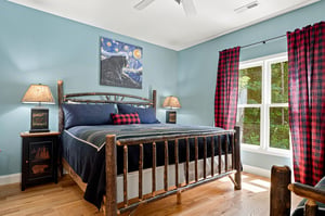Sink into your cozy rustic bed under serene blue walls, with soft natural light and charming cabin touches making every morning feel like a peaceful retreat.
