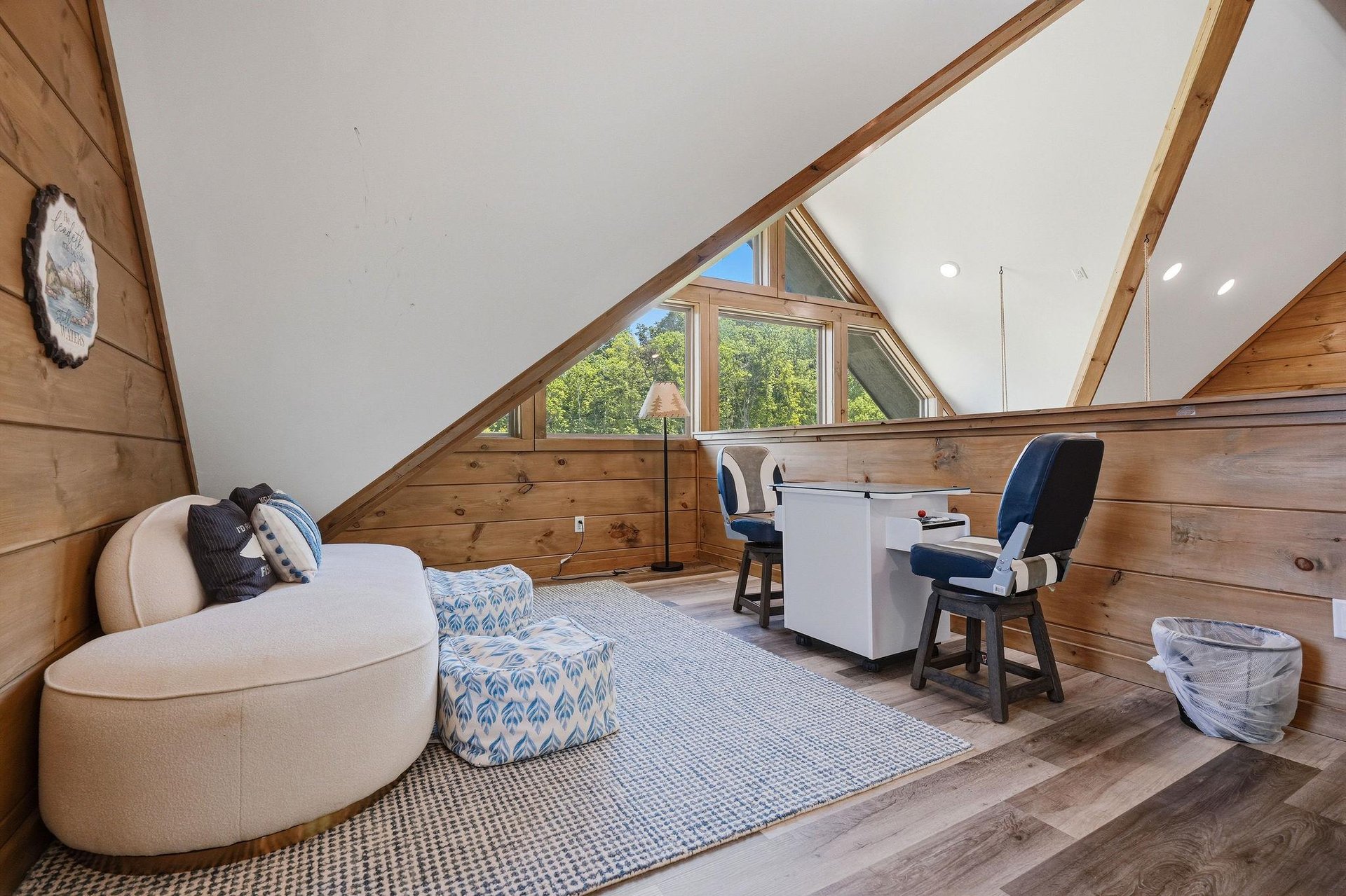 Unwind in your private loft retreat with cozy seating and peaceful forest views through the triangular windows above.