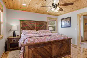 Sink into peaceful slumber on this rustic wooden bed, surrounded by warm pine details and a gentle ceiling fan breeze.