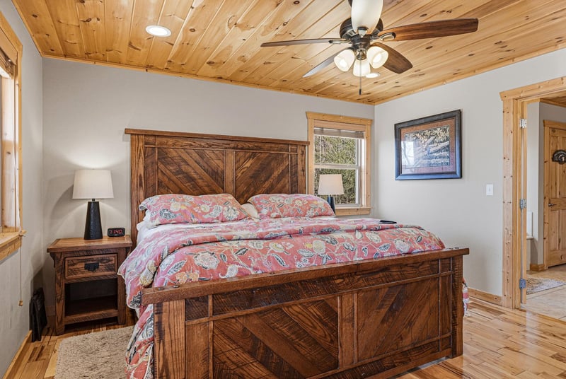Sink into peaceful slumber on this rustic wooden bed, surrounded by warm pine details and a gentle ceiling fan breeze.
