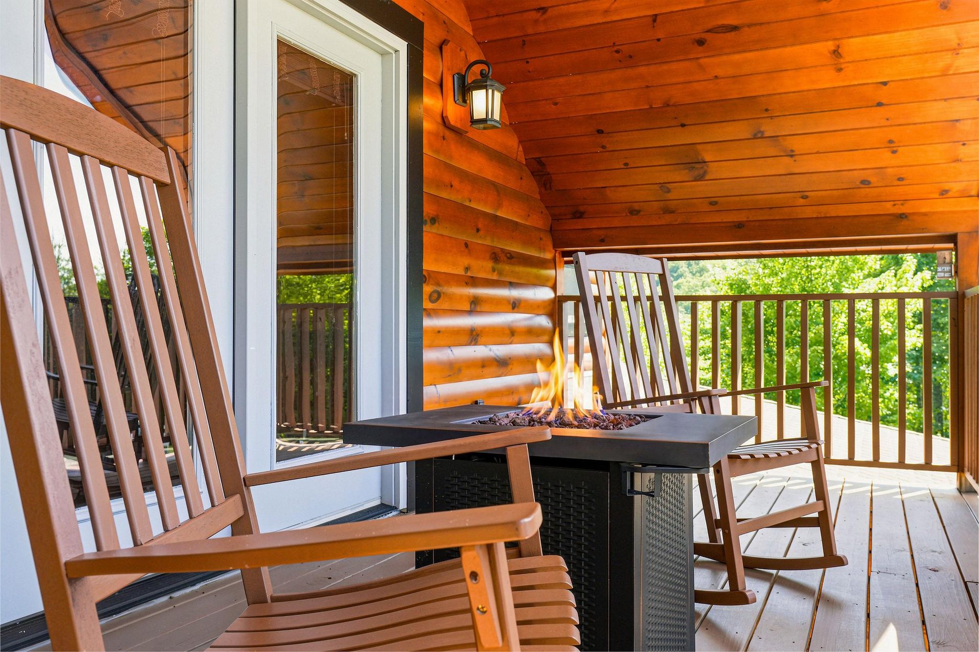 Settle into your private covered porch with rocking chairs, a cozy fire table, and peaceful wooded views—your perfect spot to unwind after exploring nearby trails.