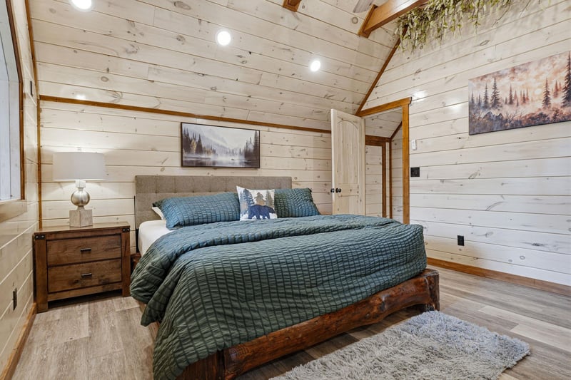Drift off peacefully in this cozy bedroom with rustic wood walls, forest artwork, and soft bedding.