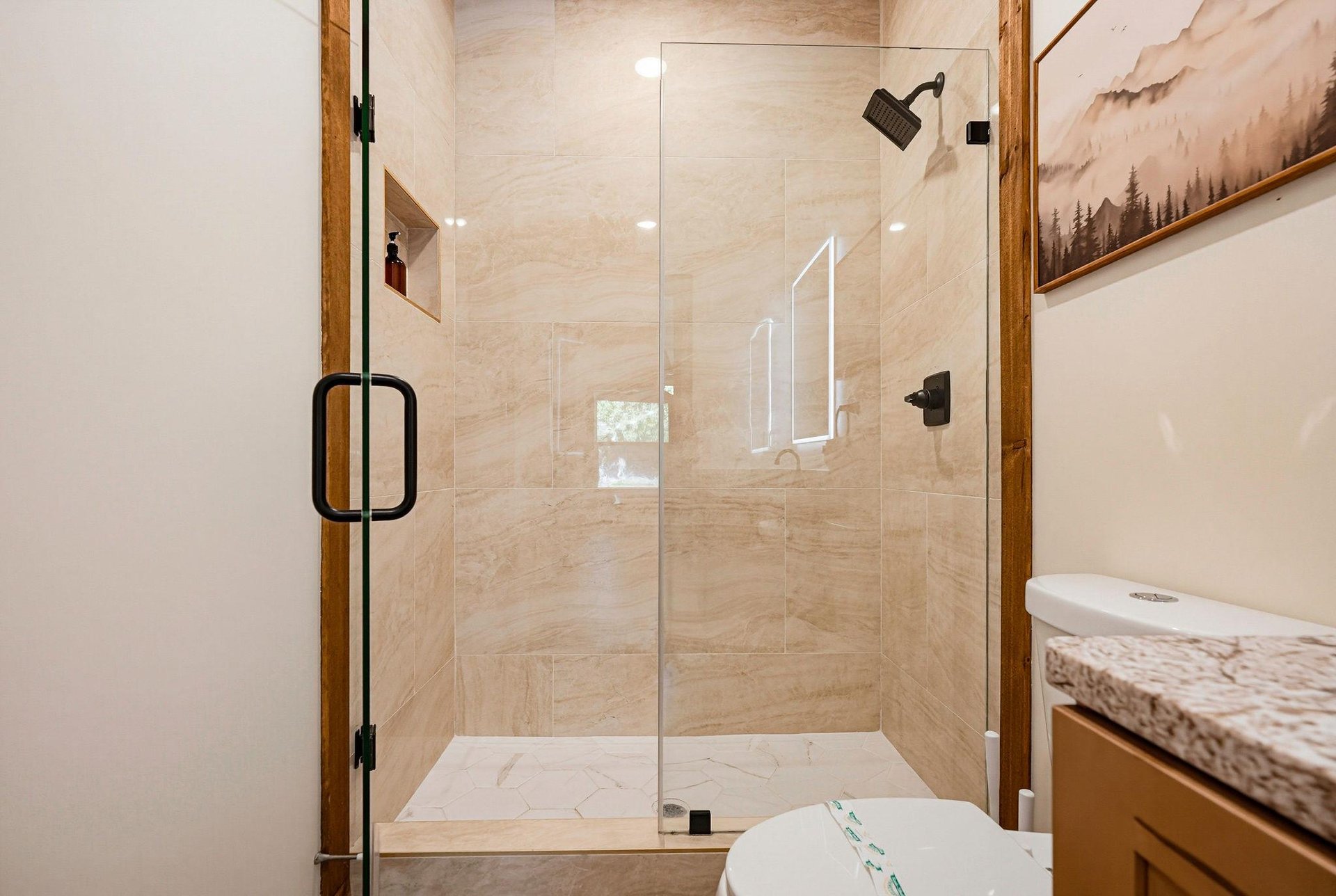 Step into your spalike bathroom, where natural wood accents frame a bright glassenclosed shower and clean lines invite relaxation after a day of exploring.