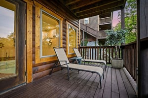 Unwind on your private deck with comfortable lounge chairs, surrounded by peaceful forest views and warm log cabin charm.