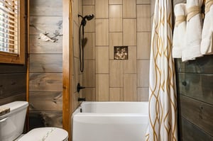 Unwind in your private bathroom featuring a tubshower combo with rustic wood plank walls, modern tile, unique stone accents, and fluffy towels ready for you.
