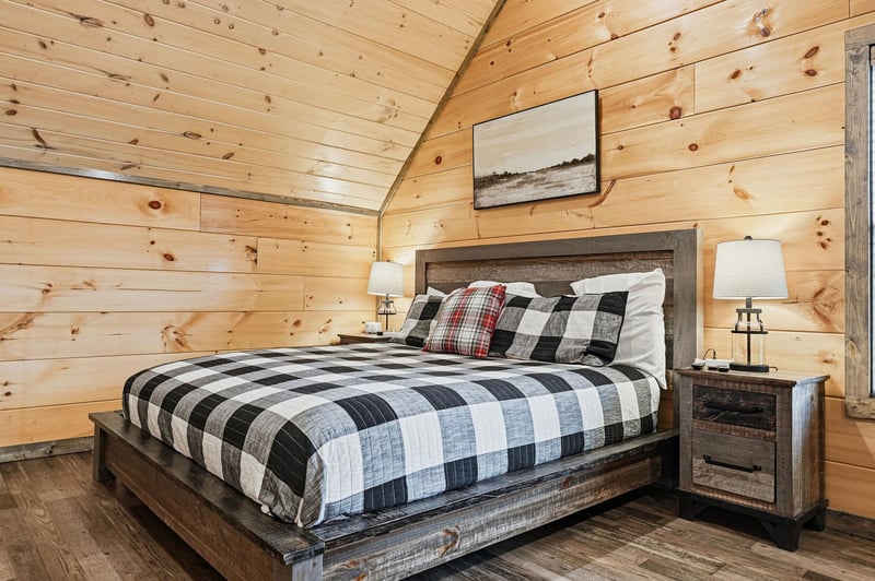 Unwind in your cozy rustic bedroom with warm wood walls, plaid bedding, and charming cabin details for the perfect mountain retreat.