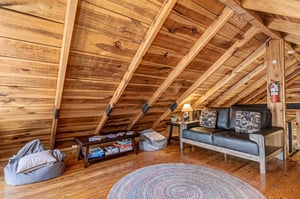 Relax in your private loft retreat with exposed wood beams, cozy seating, and a charming reading nook perfect for unwinding.