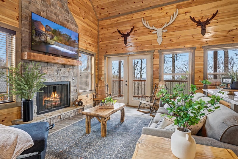 Cozy up by your crackling fireplace in this rustic living room, where warm wood walls and mountain decor create the perfect cabin retreat.