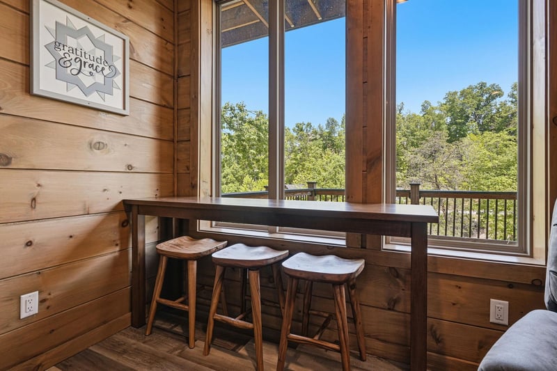Savor your morning coffee at this cozy breakfast bar while enjoying peaceful forest views through expansive windows.