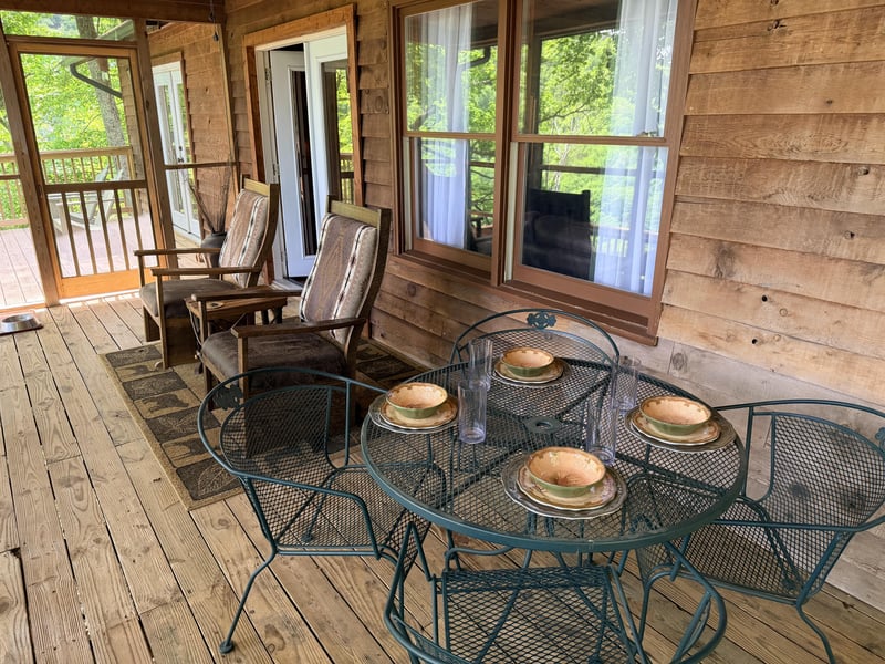 Your private screened porch invites peaceful mornings with fresh air, garden views, and space for four at the metal dining set—perfect for coffee or evening meals.