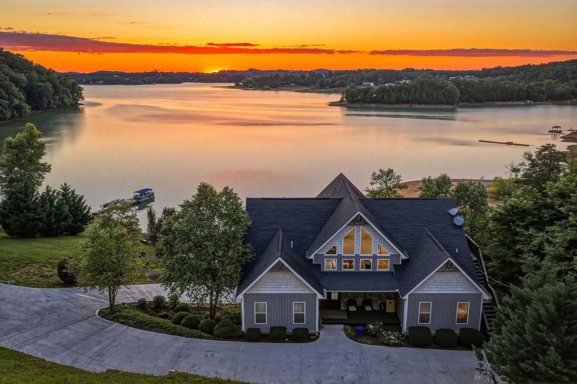Stunning lakefront property captured at sunset, showcasing the homes prime location with expansive water views, private dock access, and surrounding natural landscape.