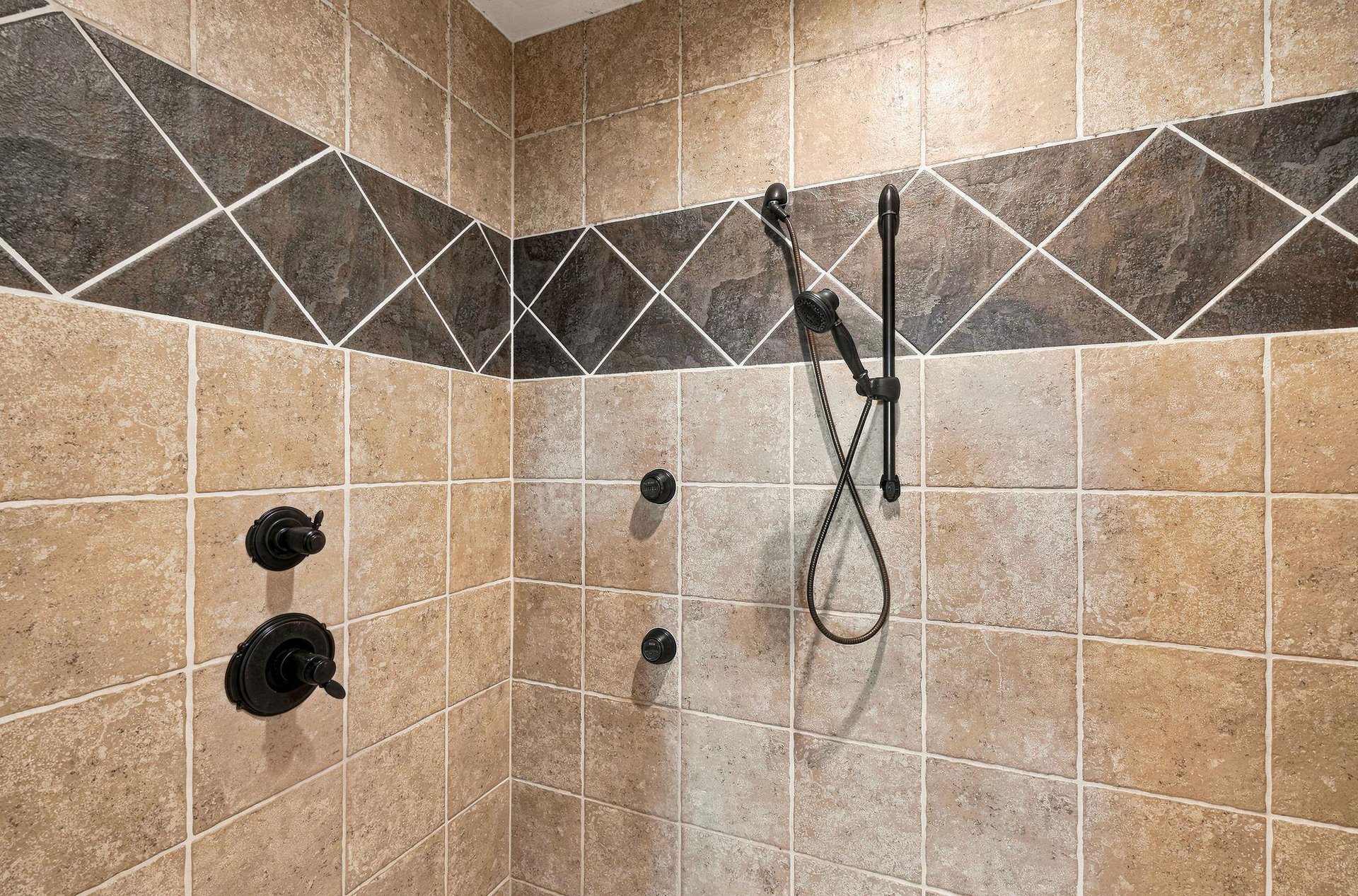 Rinse away your cares in this beautifully tiled walkin shower with dual fixtures and elegant bronzetoned hardware.