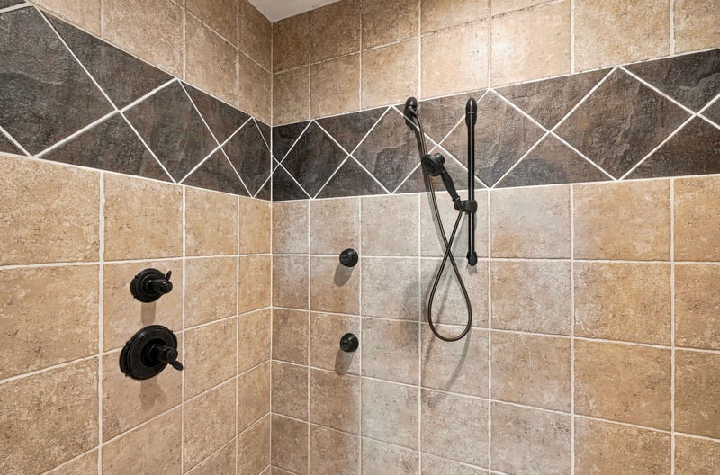 Rinse away your cares in this beautifully tiled walkin shower with dual fixtures and elegant bronzetoned hardware.