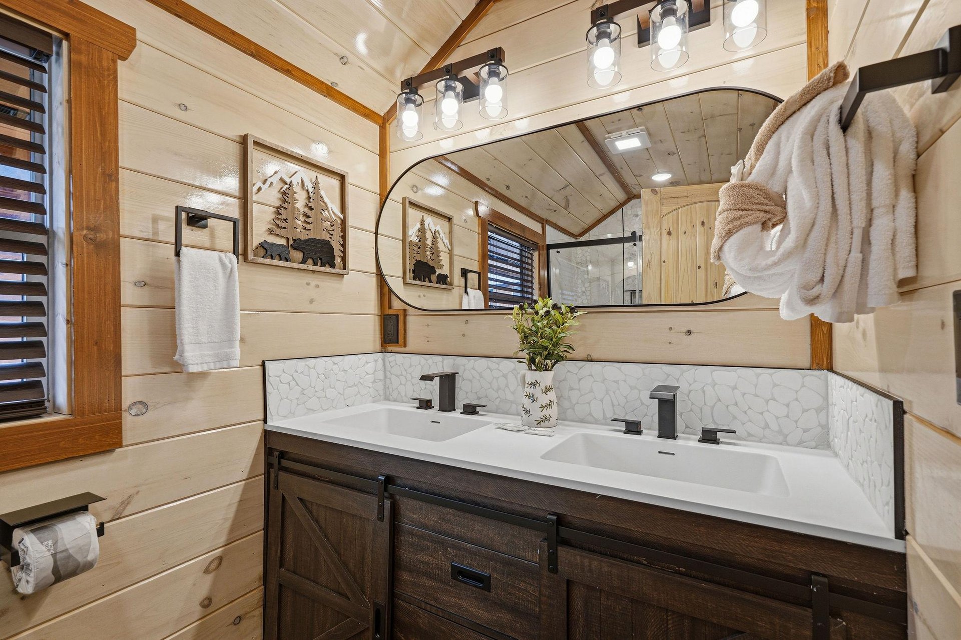 Step into your beautifully appointed bathroom featuring dual sinks, rustic wood accents, and plush towels ready for your mountain retreat.