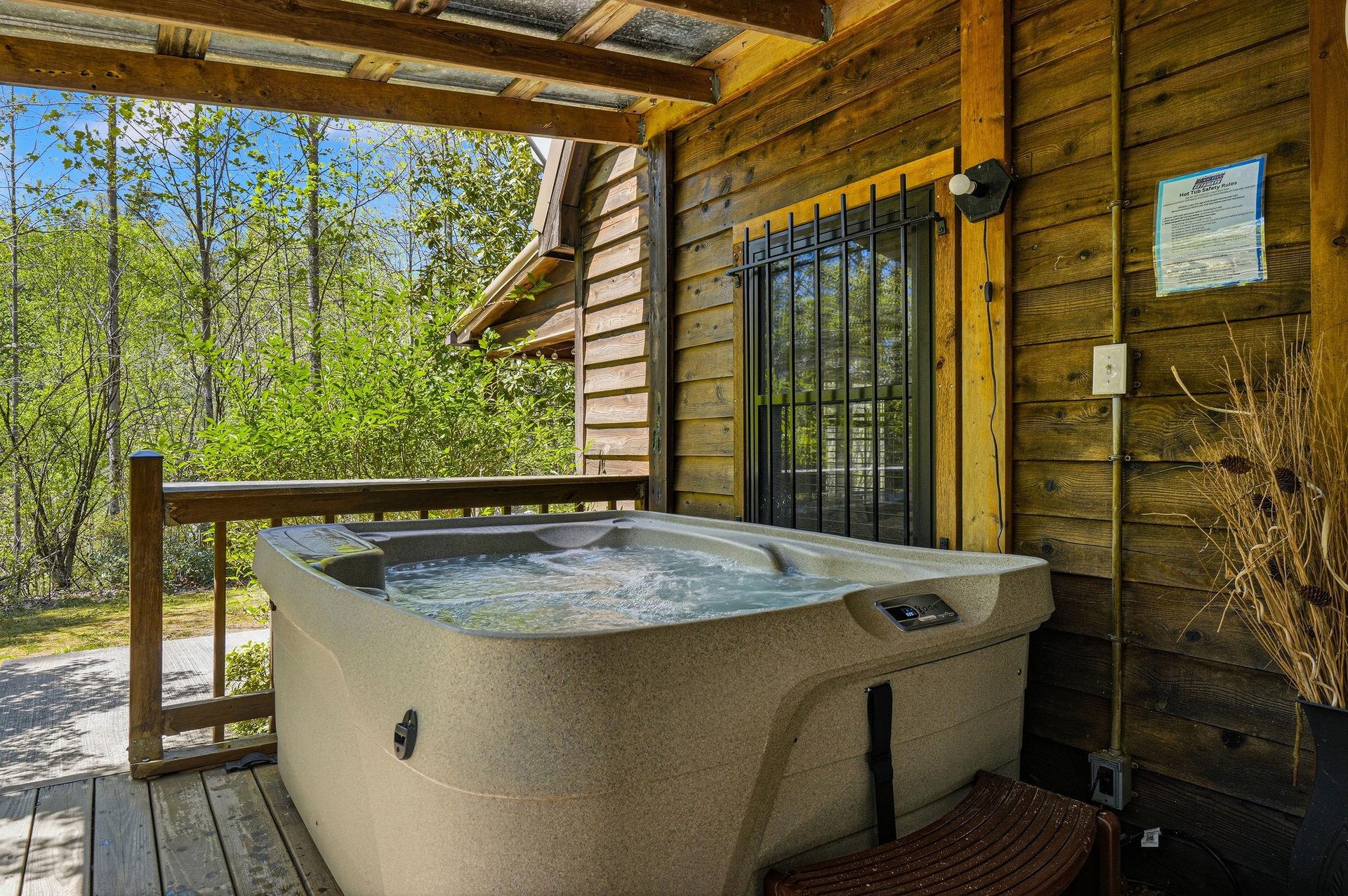 Soak in your private hot tub while surrounded by lush greenery and peaceful woodland views from this covered deck.