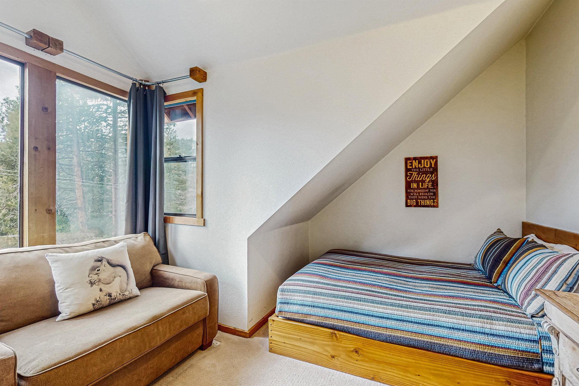 This upstairs bedroom features a queen bed, a cozy loveseat, a dresser, a wallmounted clothing rack and shelf, ceiling fan, and recessed lighting.