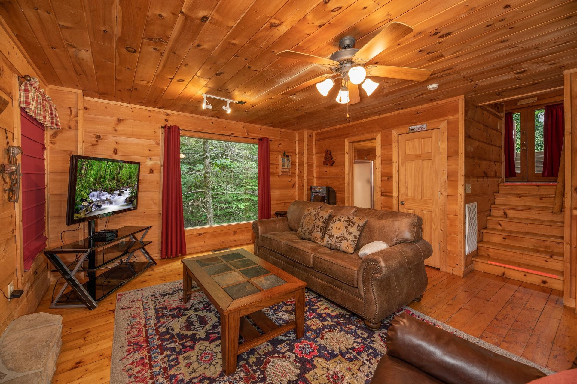 TV, picture window, and sofa in the living room at Logans Smoky Den, a 2 bedroom cabin rental located in Pigeon Forge